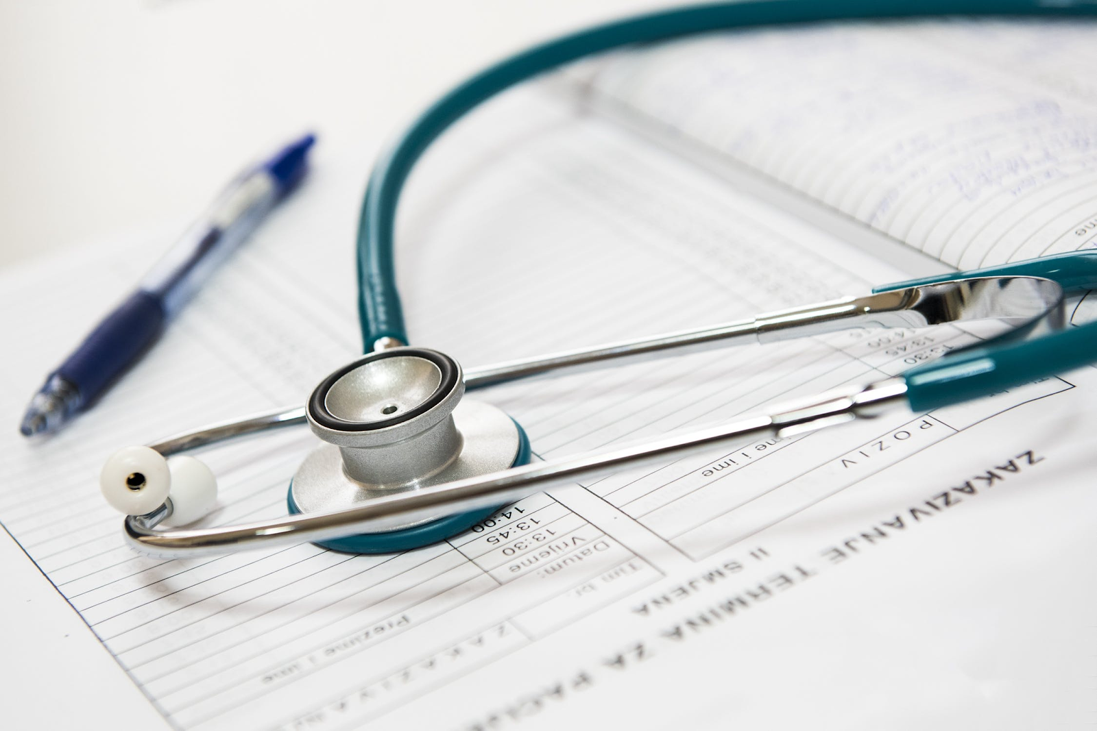 Stethoscope and a pen lying on a doctor's notebook, Medical data 